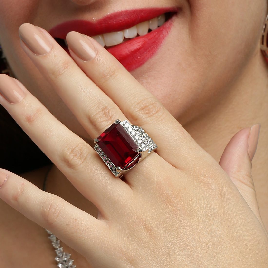 Model wearing 925 sterling silver ruby statement ring with red emerald-cut gemstone and pavé diamond detailing