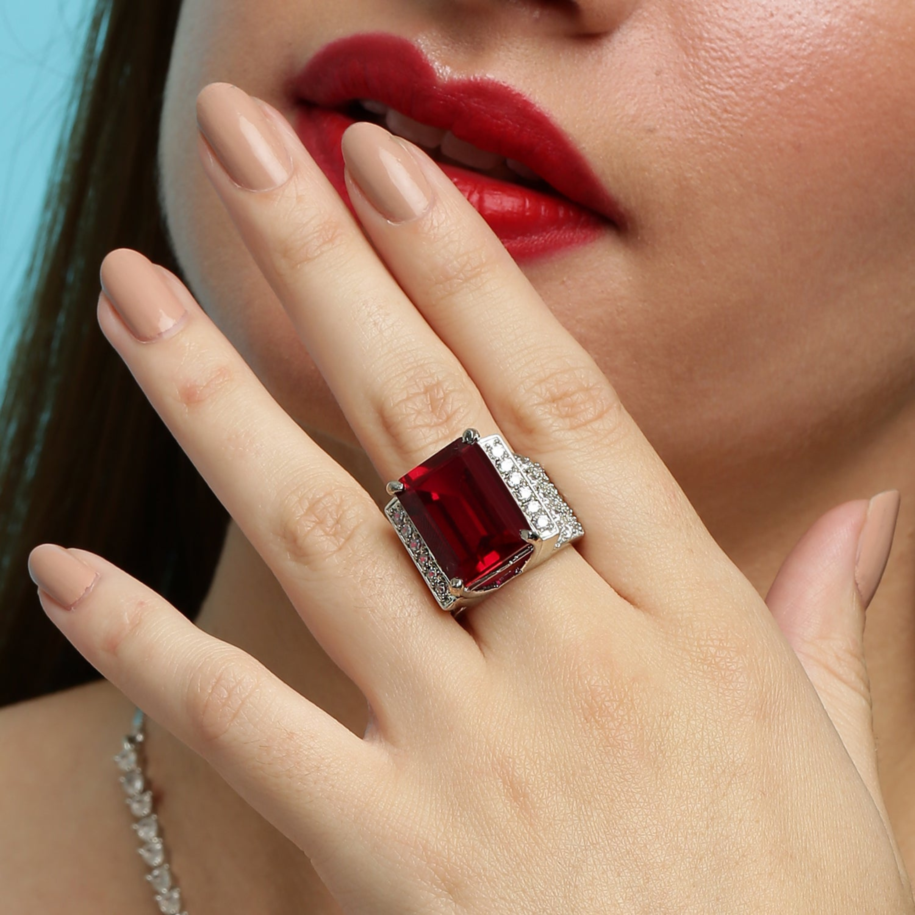 Close-up of model wearing 925 sterling silver ruby statement ring with red gemstone and diamond pavé band