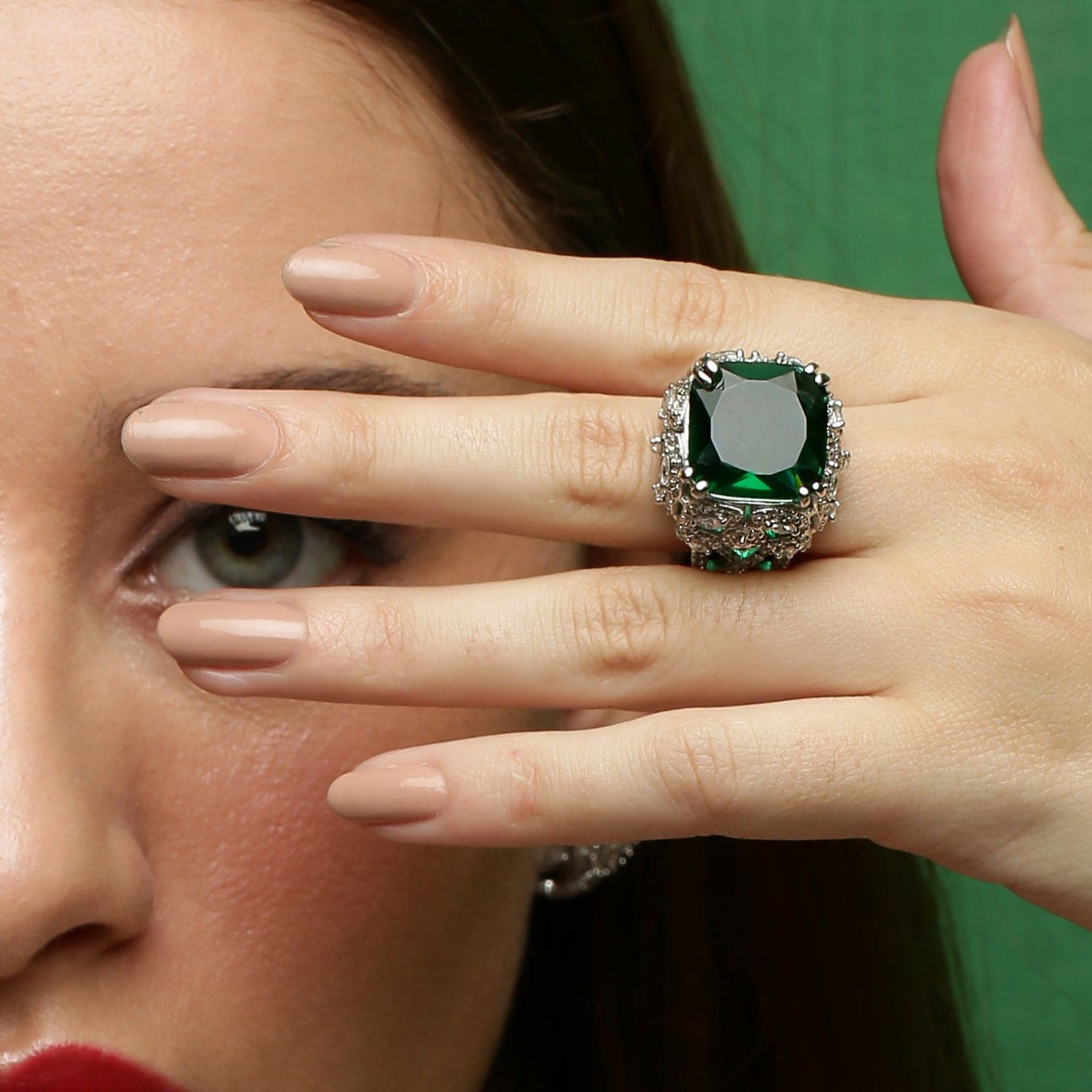 Premium emerald statement ring on a model hand with brilliant white stones, elegant luxury jewellery photography