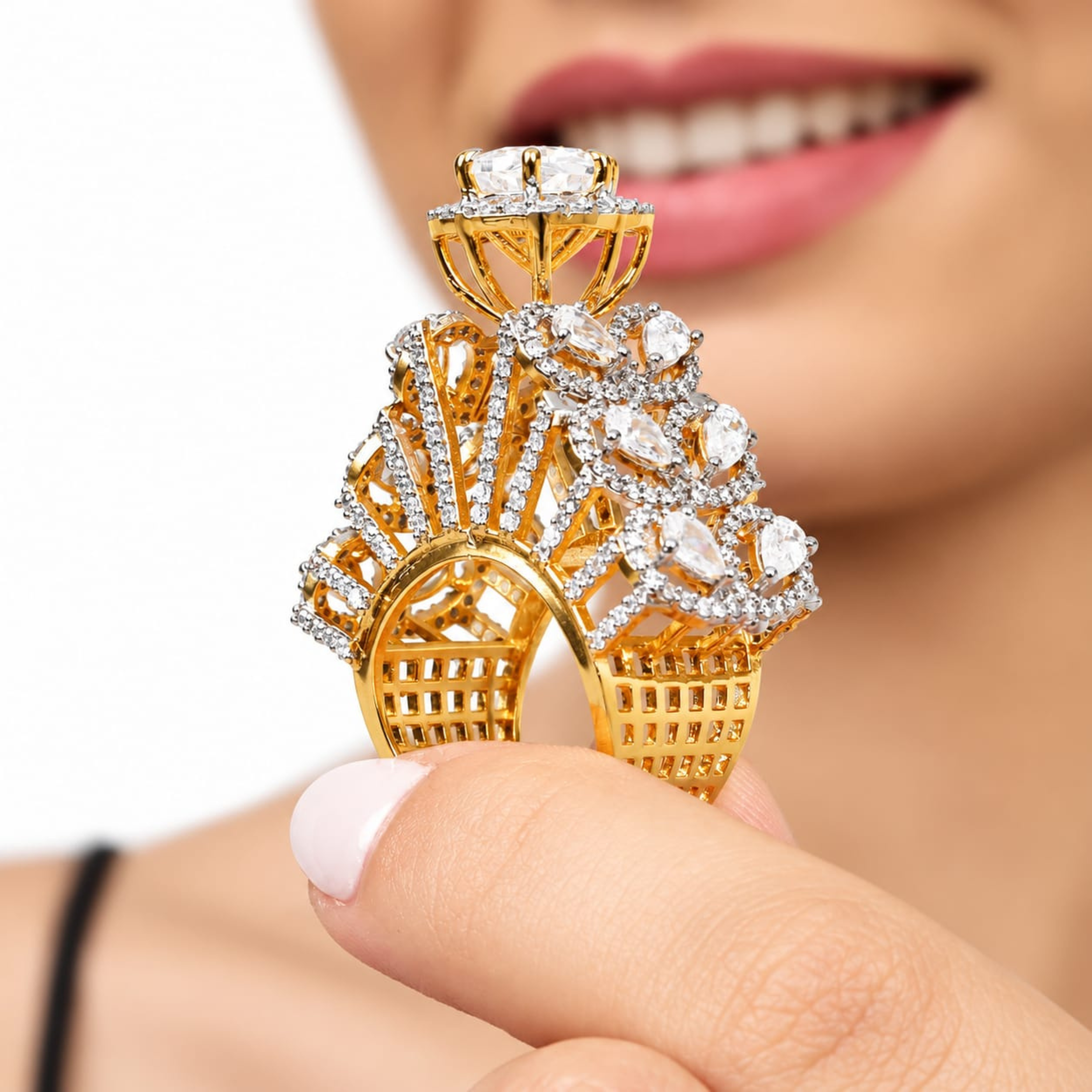Gold-plated statement cocktail ring with large round zircon centre stone, pear-cut cubic zirconia and sparkling halo accents, held between fingertips